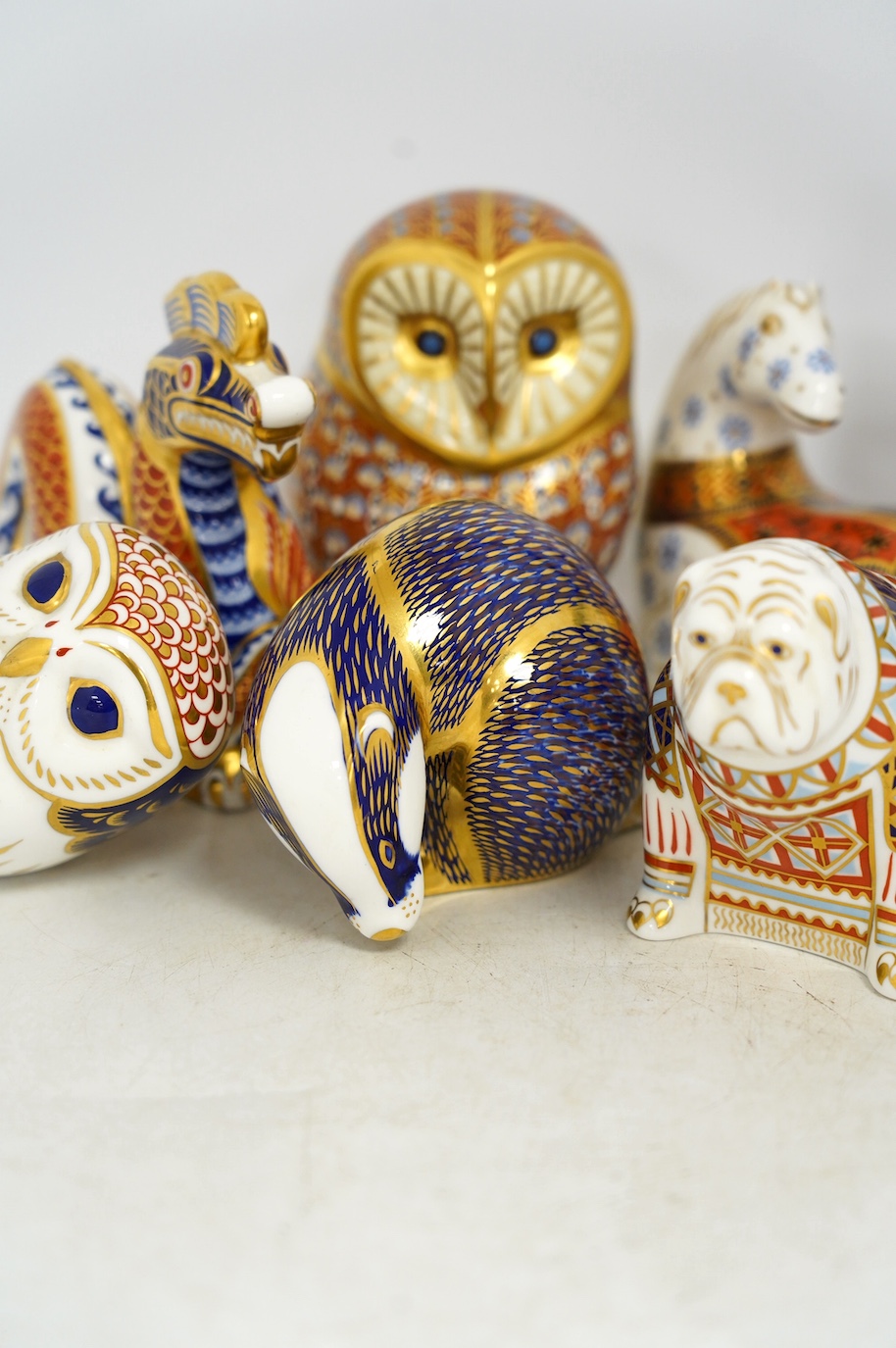 Eight Royal Crown Derby porcelain paperweights in the form of animals including a cat, badger and owl, largest 13.5cm high. Condition - good
